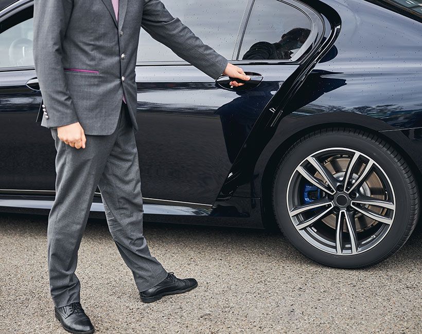 A chauffeur opening a car door ready to transport a customer